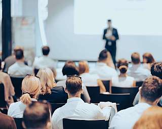 Teilnehmer hören einem Vortrag in einem Konferenzraum zu.