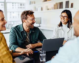 Vier Personen in einem Meeting, die lachen und diskutieren.