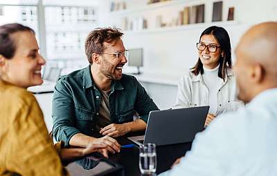 Vier Personen in einem Meeting, die lachen und diskutieren.