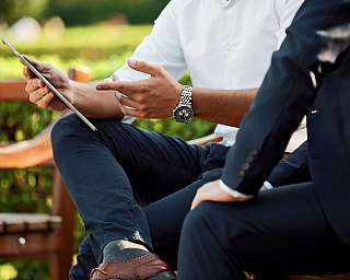 Zwei Männer diskutieren, während sie ein Tablet in einem Garten halten.