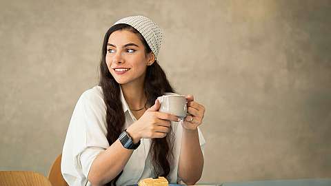 Junge Frau genießt Kaffee und Gebäck in einem Café.
