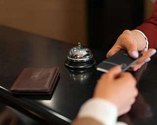 Ein Gast reicht einem Empfangsmitarbeiter ein Smartphone in einem Hotel.