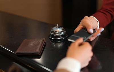 Ein Gast übergibt ein Telefon an der Hotelrezeption.