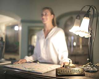A receptionist at a desk with a map and lamp.