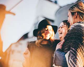 Drei Frauen lachen und teilen einen Moment im Freien.