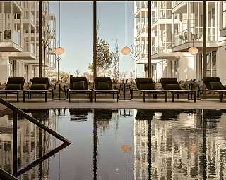 Innenpool mit Liegestühlen und großen Fenstern.